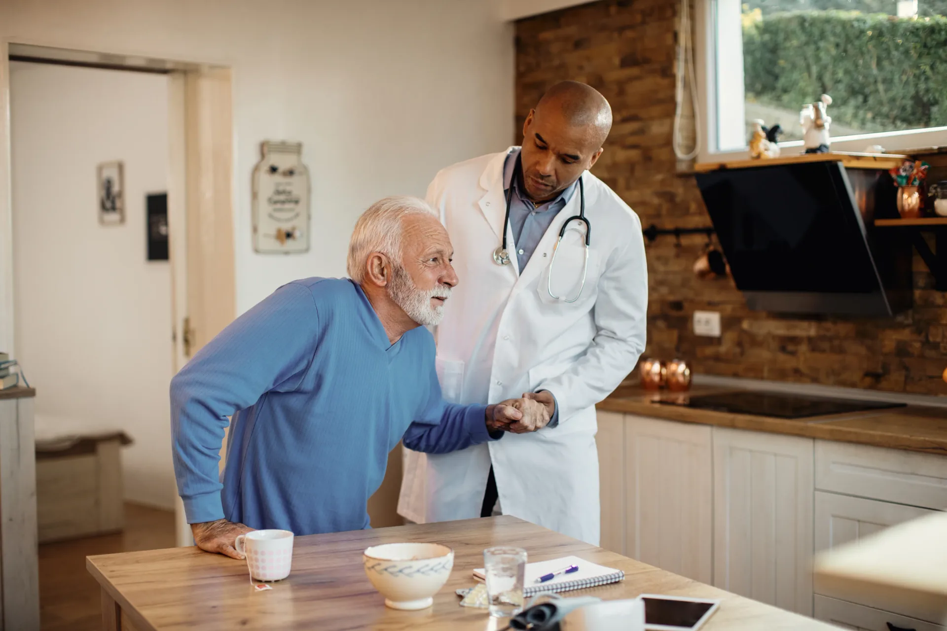 Healthcare worker helping an older person stand safely at home