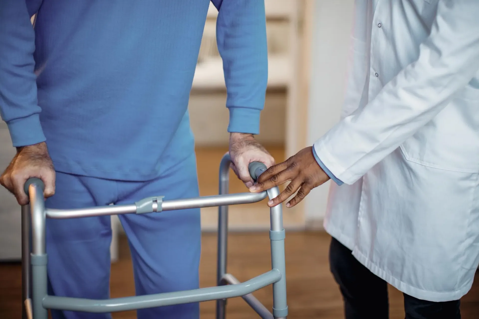 Care worker supporting mobility with a walking frame